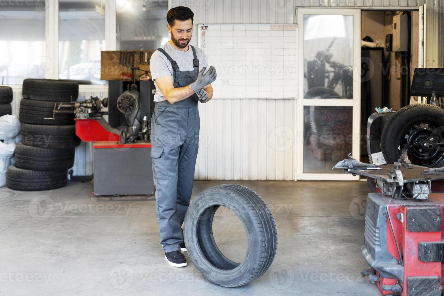 Mechanic wearing overalls putting gloves on in a garage photo