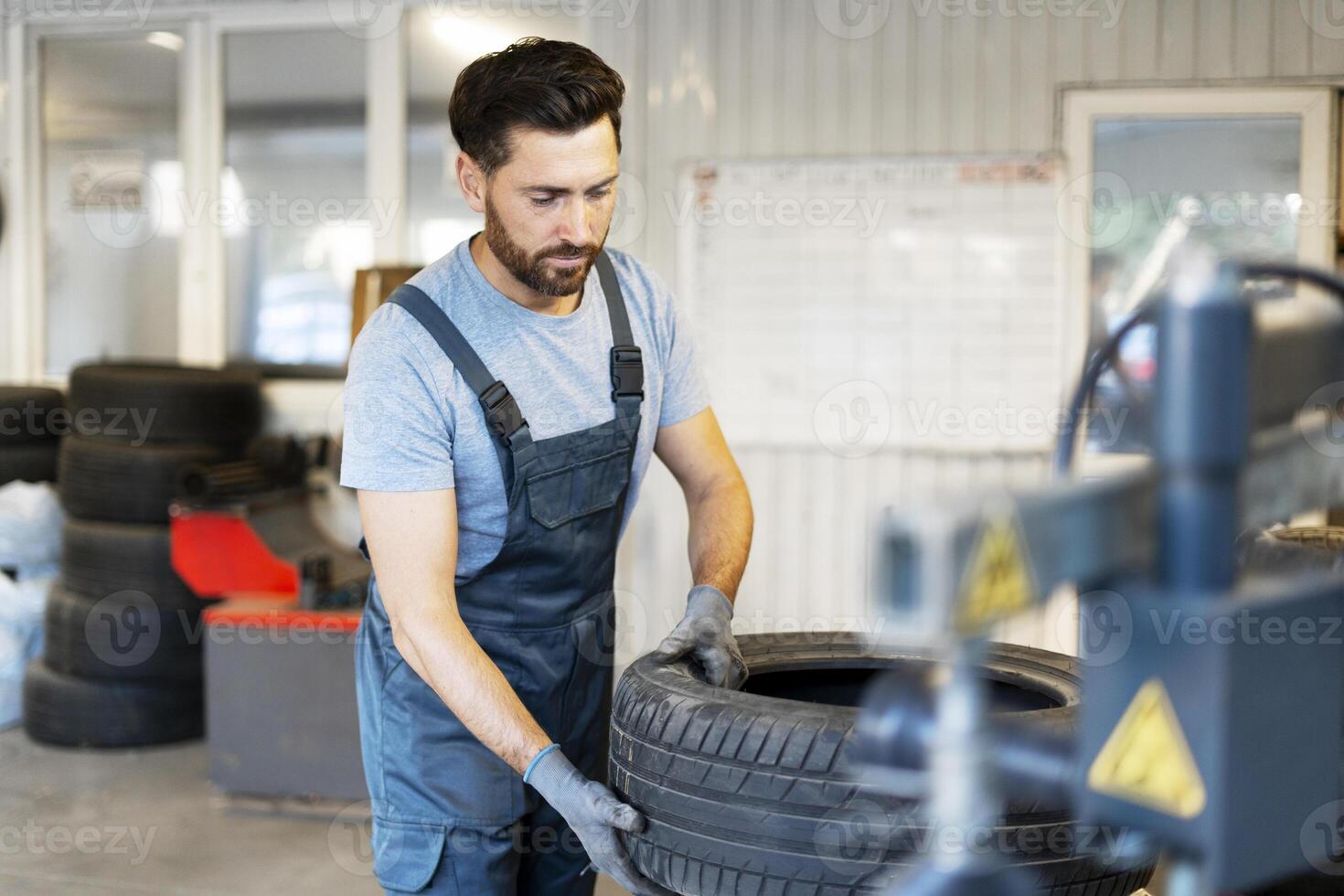 Mechanic picking up car tire for seasonal change in garage photo