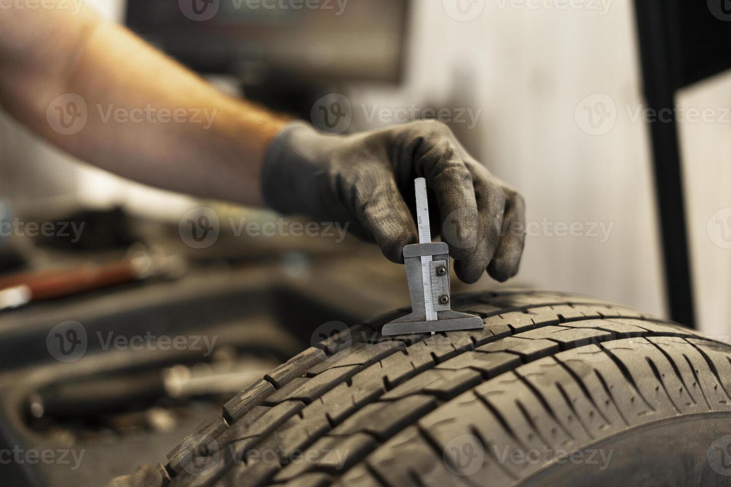 Mechanic measuring tyre tread depth using caliper photo