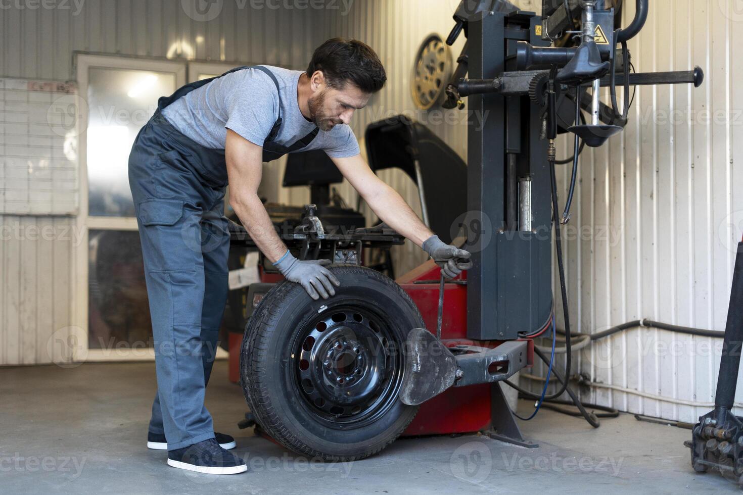 Mechanic mounting a tire on a tire changer machine in a workshop photo