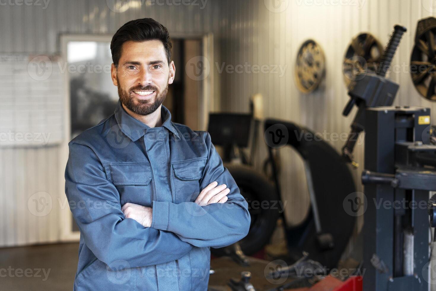 Mechanic smiling with crossed arms in auto repair shop photo