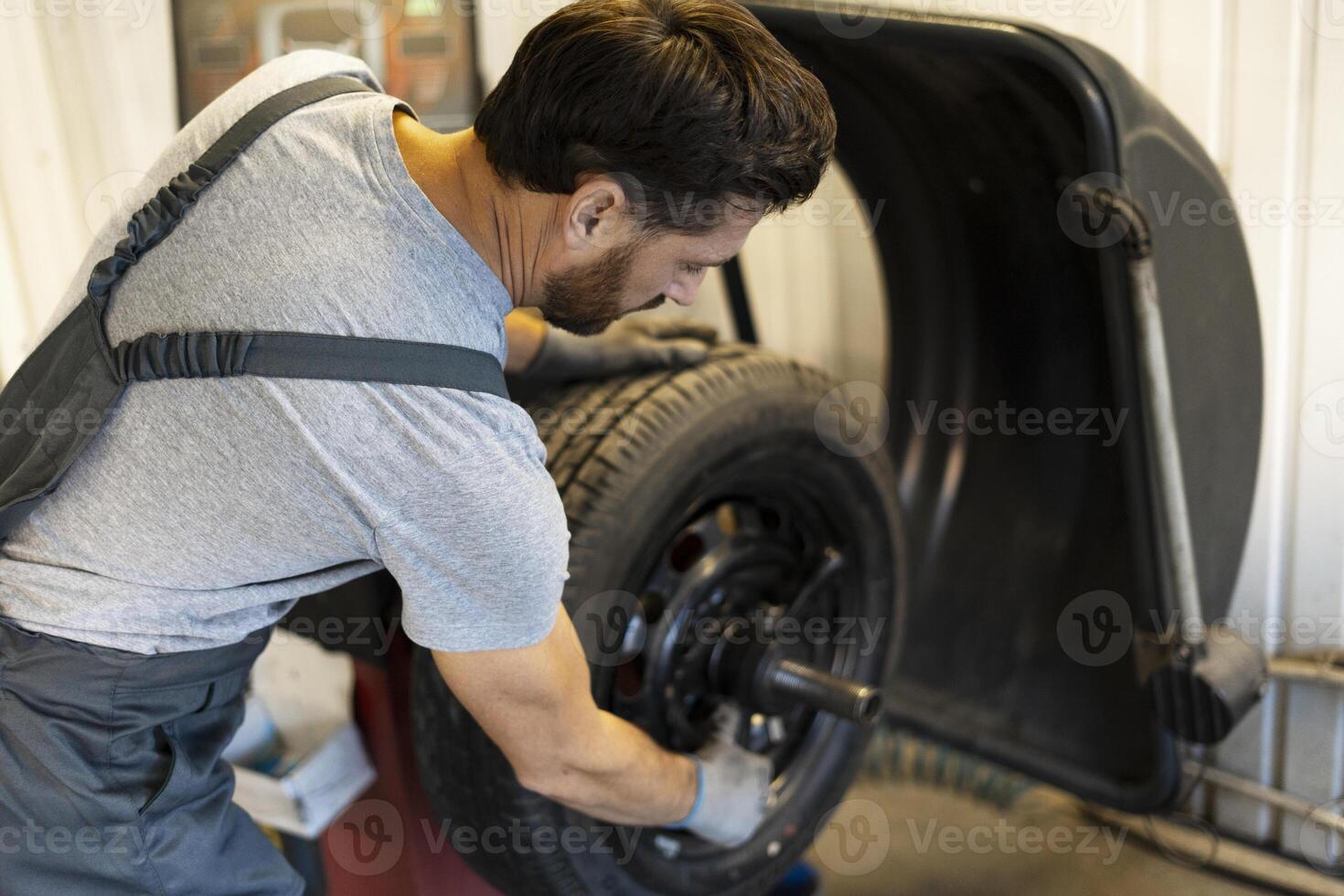 Mechanic mounting new tyre on wheel in auto repair shop photo