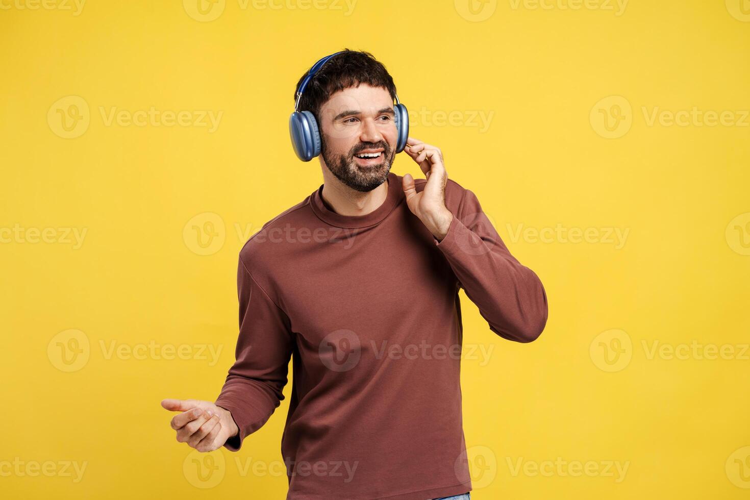 Portrait of smiling, happy middle aged man listening music in earphones, dancing, looking away photo