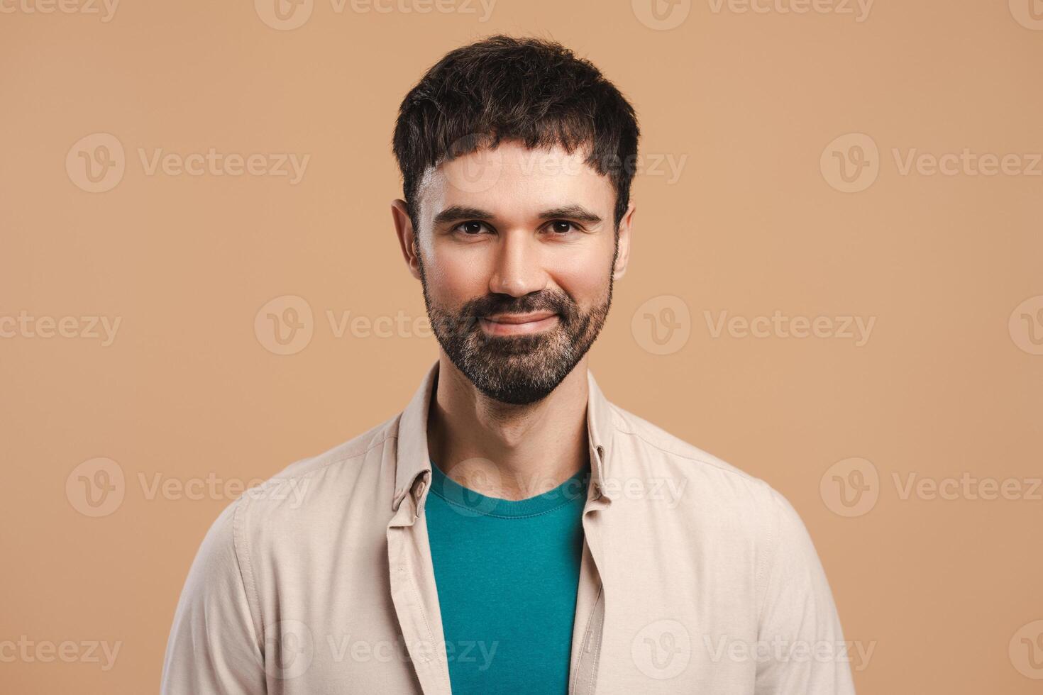 Portrait of smiling, happy Latin man looking at camera, posing isolated on beige background photo