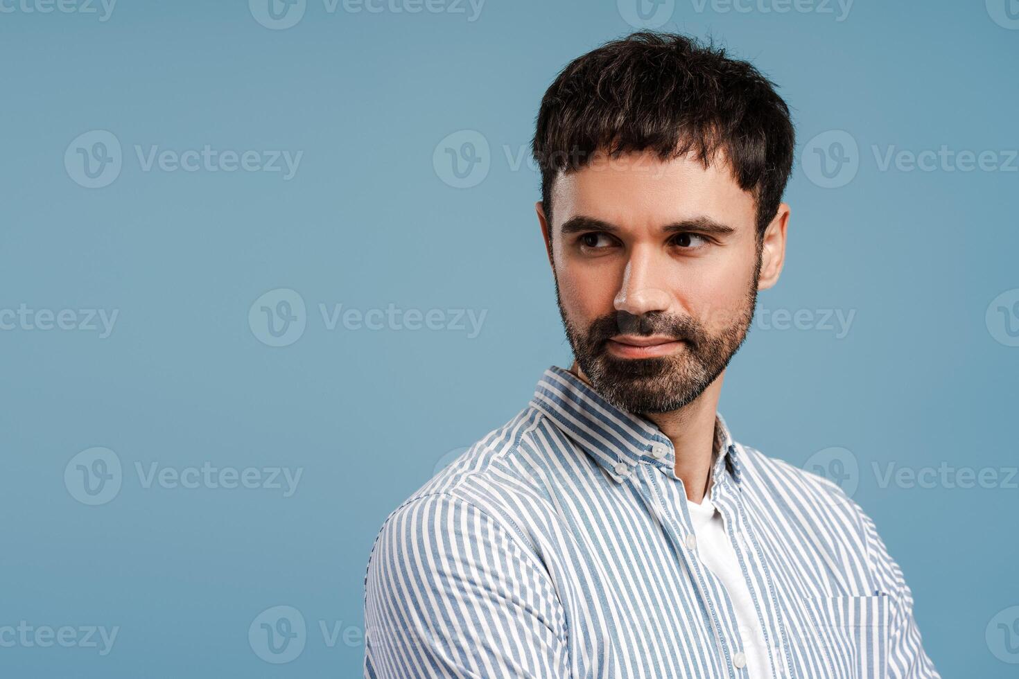 Attractive, confident man wearing blue shirt looking away standing isolated on blue background photo