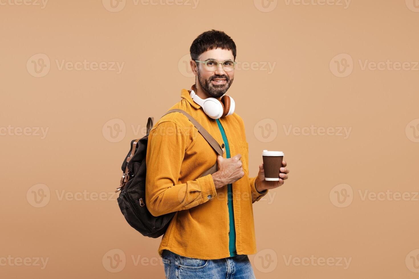 Happy Latin man, student wearing stylish eyeglasses, holding backpack and paper cup with coffee photo