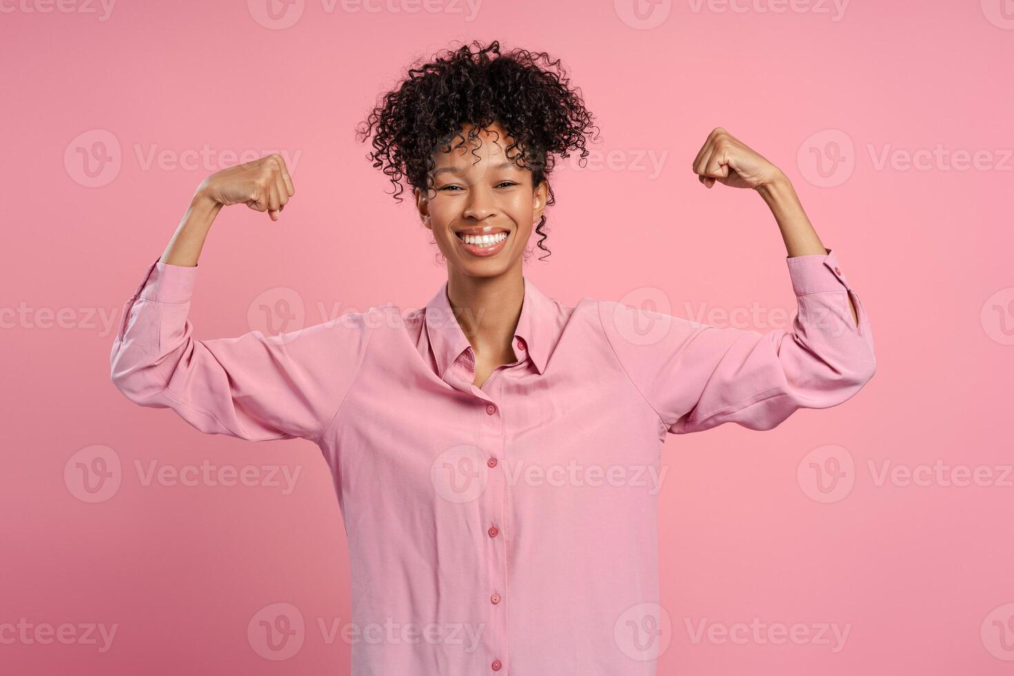 Portrait of excited African American woman showing biceps rejoicing isolated photo
