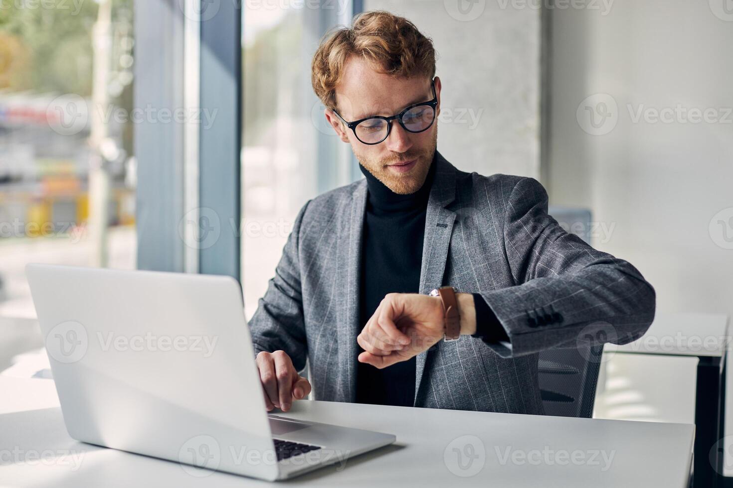 Busy manager checking time working on laptop in office photo