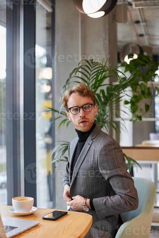 Businessman buttoning his jacket in a cafe photo