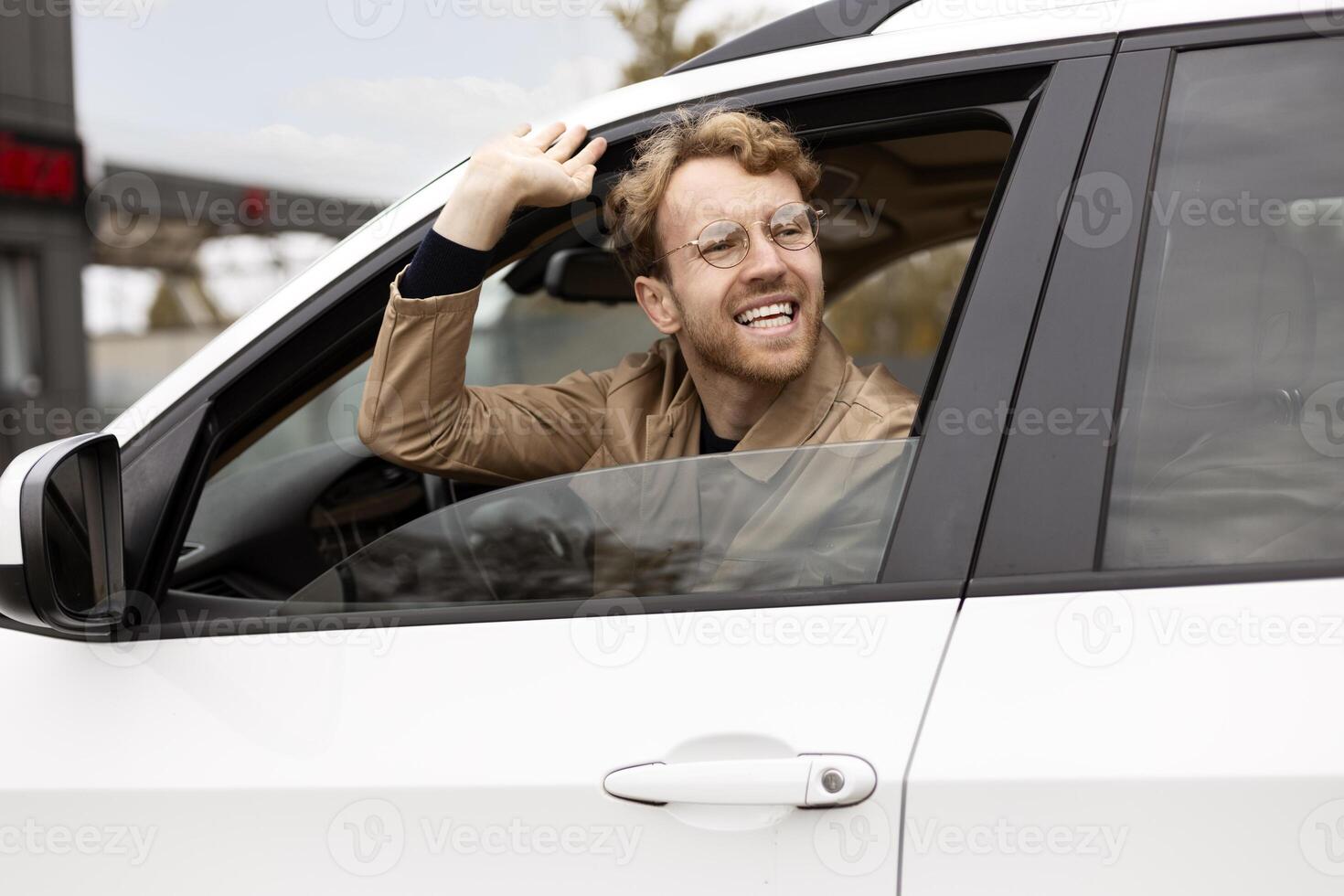 Happy businessman waving from car window photo
