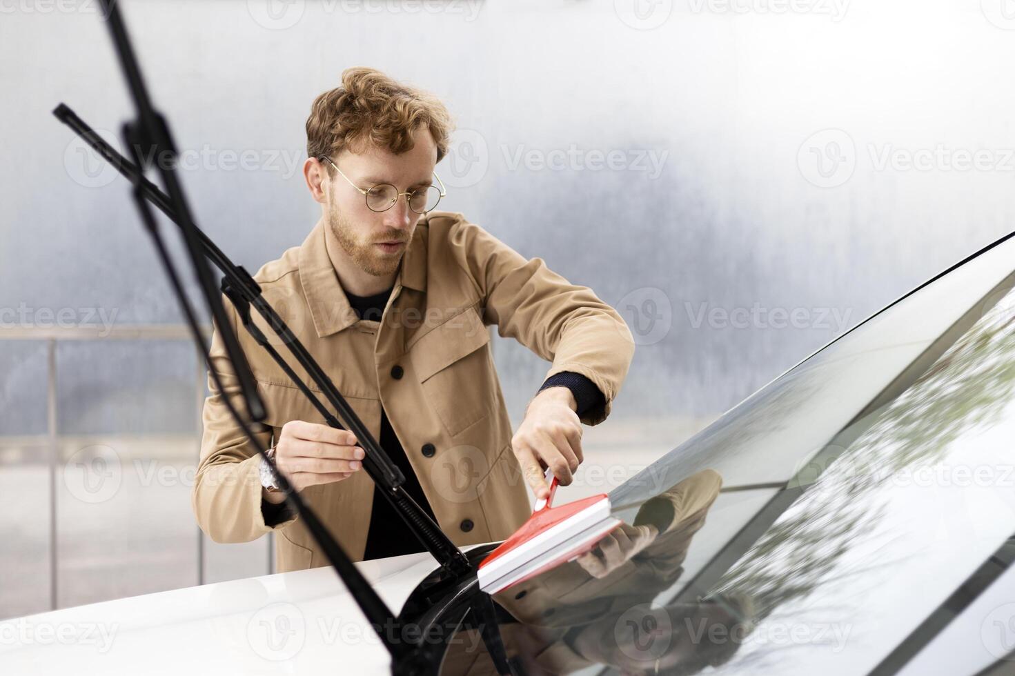 Mechanic cleaning windshield of car with squeegee photo