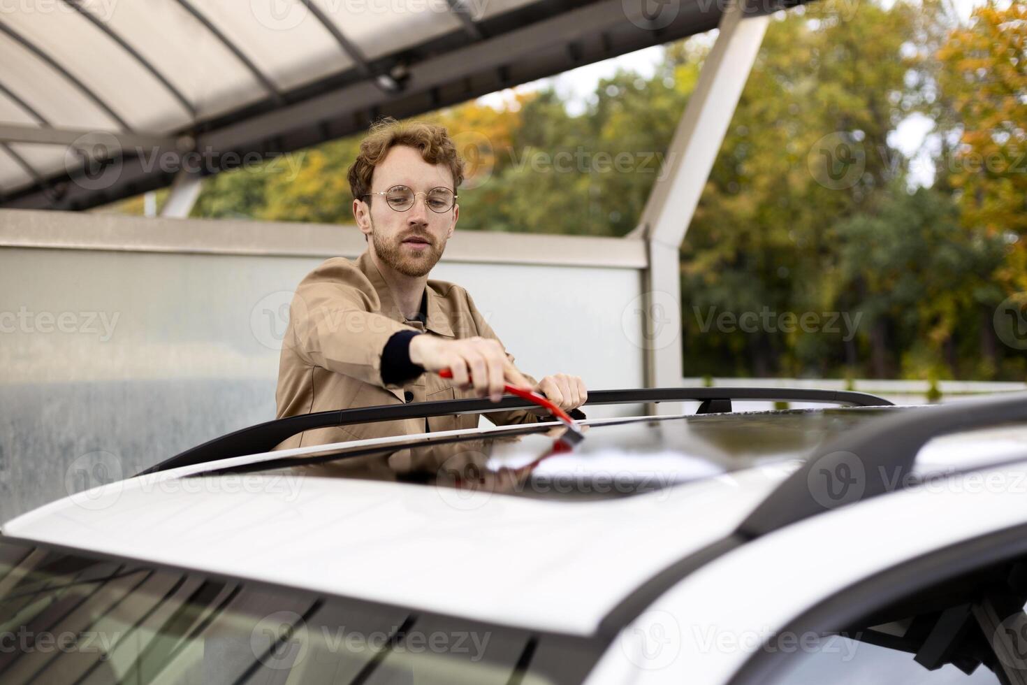 Car detailing service worker cleaning roof of white car with brush photo