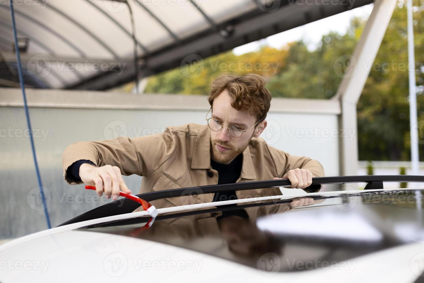 Focused man cleaning car roof with brush in self service car wash photo