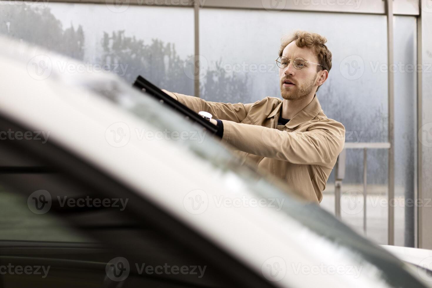 Mechanic fixing car windshield wiper in repair shop photo