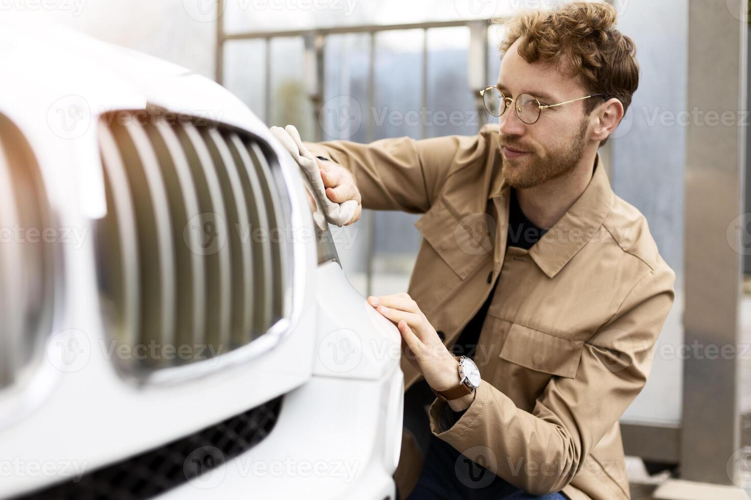Car detailing job mechanic polishing white car with microfiber cloth photo