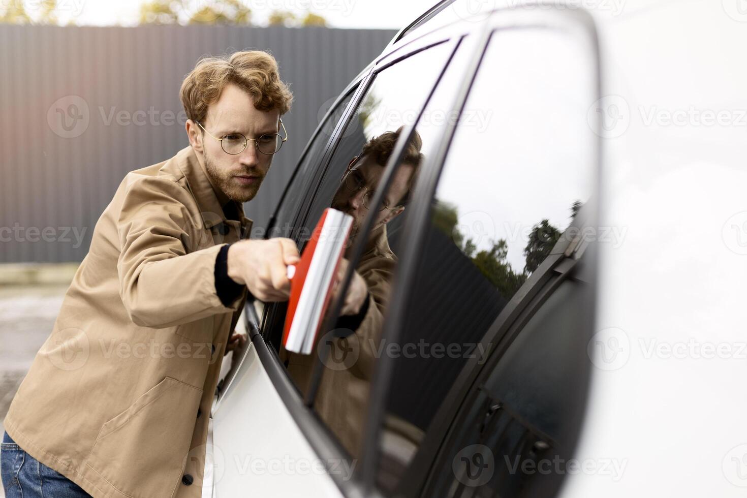 Young man cleaning his car with a squeegee photo