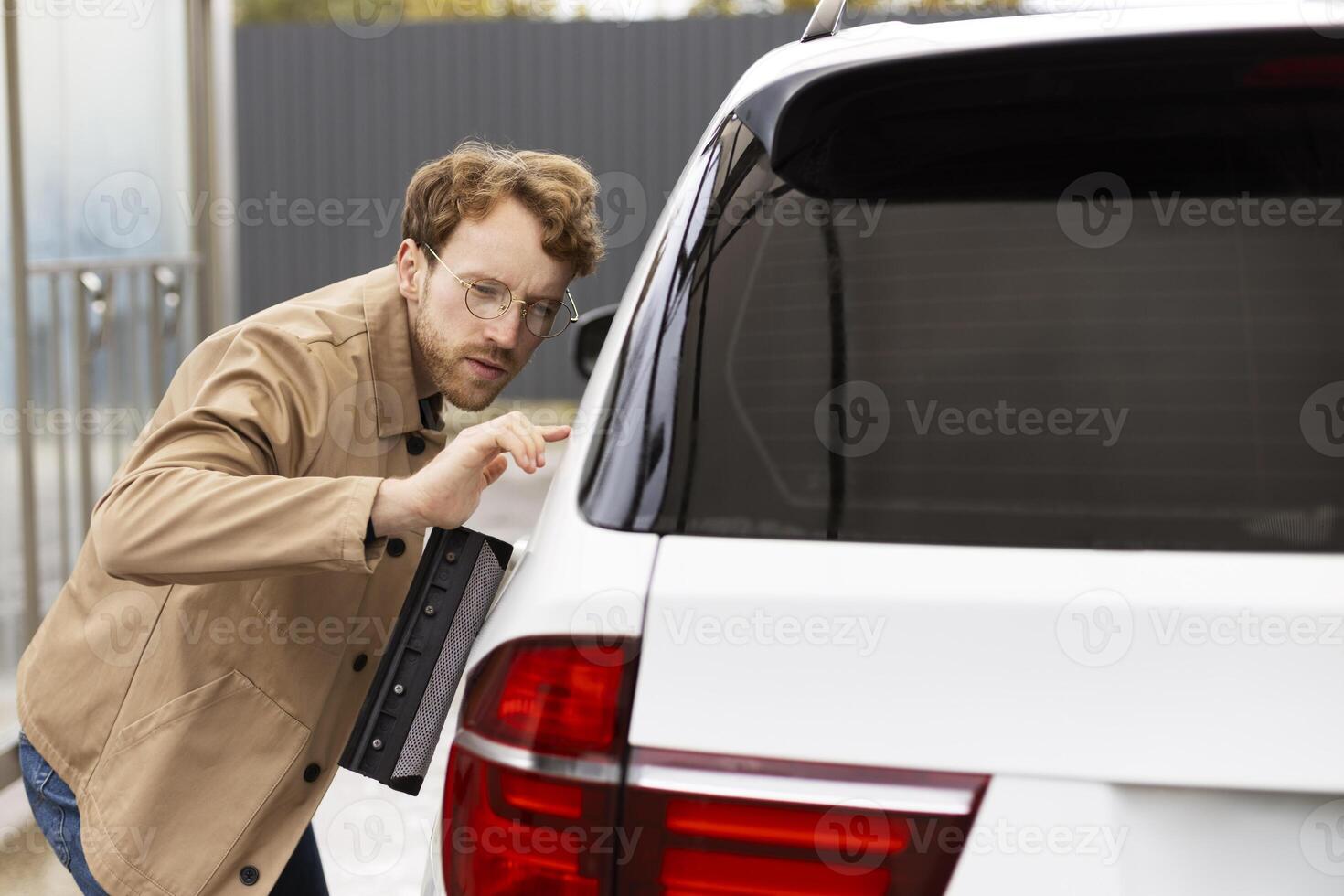 Professional car detailer examining paint for imperfections photo