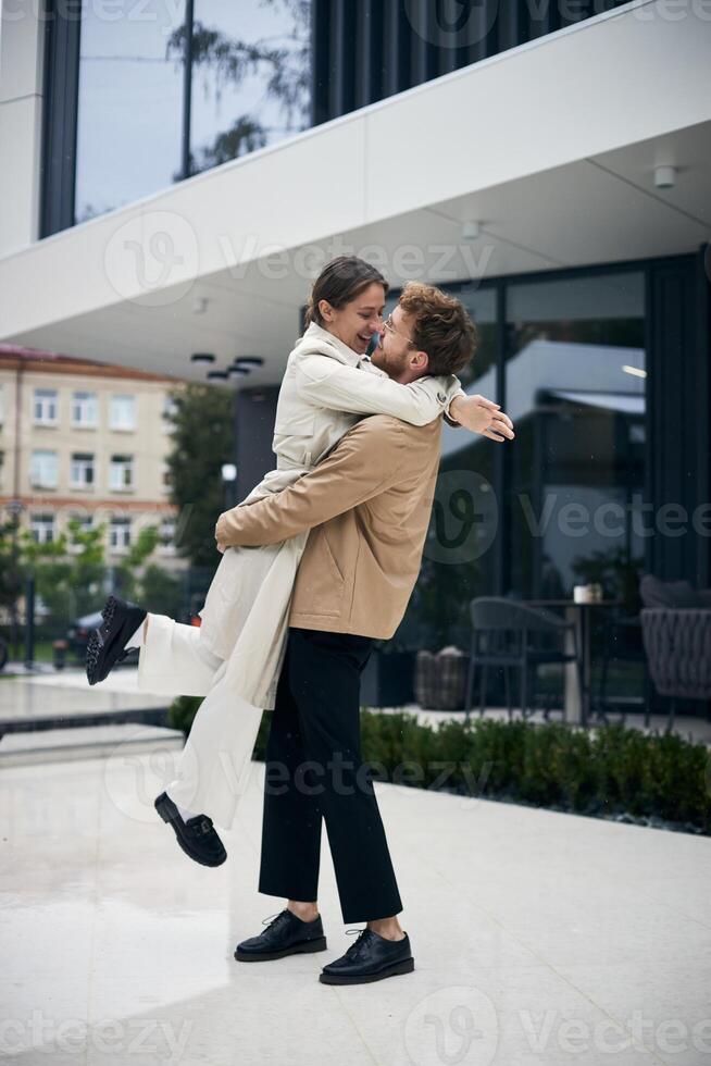 Happy couple embracing in front of modern building photo