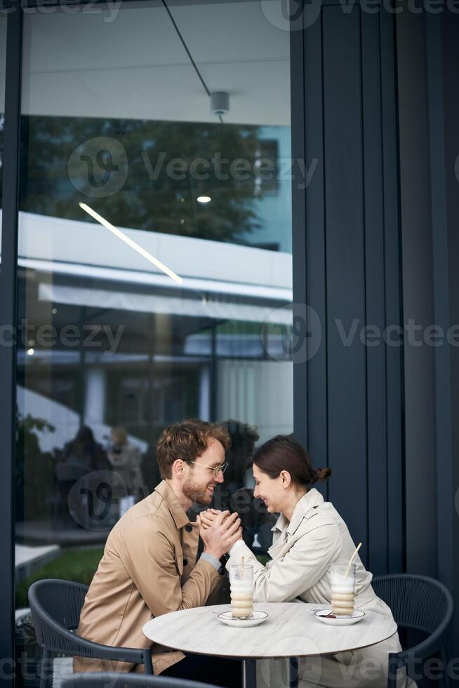 Young couple holding hands and looking at each other in outdoor cafe photo