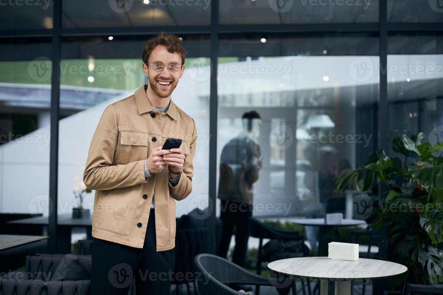 Stylish man smiling while using smartphone at a cafe photo