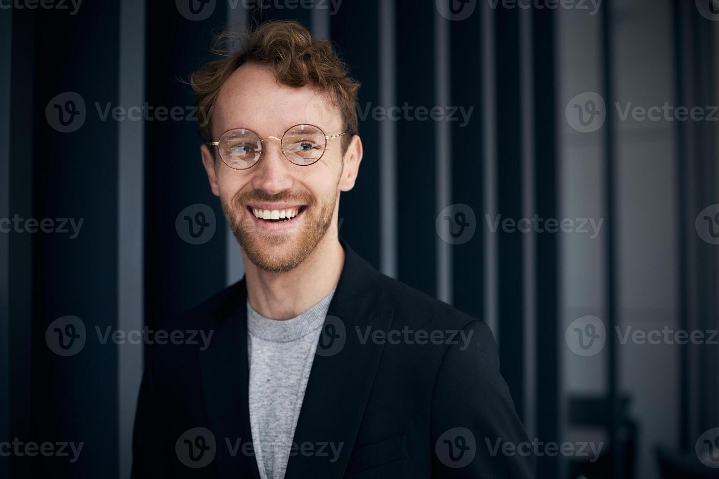 Young professional smiling wearing glasses and blazer photo