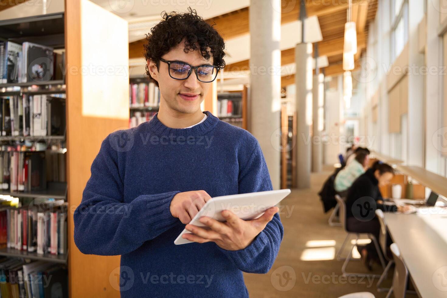 Young man using digital tablet while standing in library photo