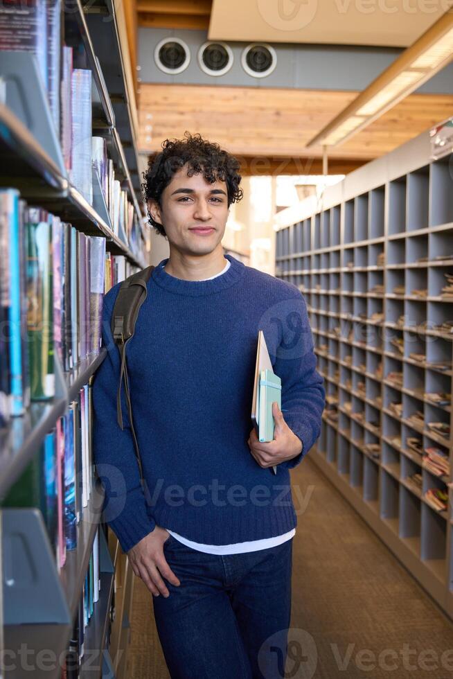 University student holding books and walking in library photo