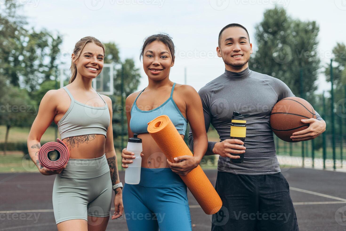 Smiling, happy multiethnic women and man holding sport equipment, looking at camera photo