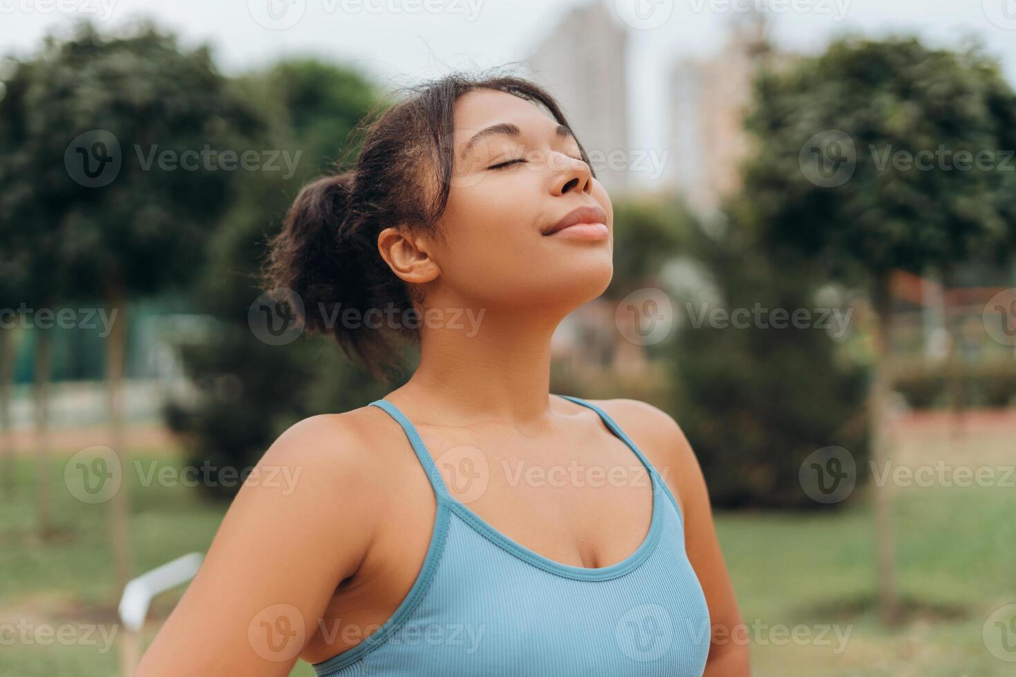 Beautiful young African American woman wearing sportwear with closed eyes breathing on the street photo