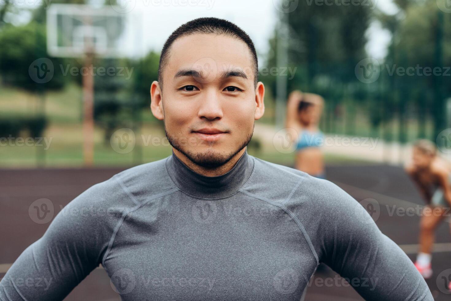 Portrait of handsome, smiling Asian man wearing sportwear looking at camera, posing outdoors photo