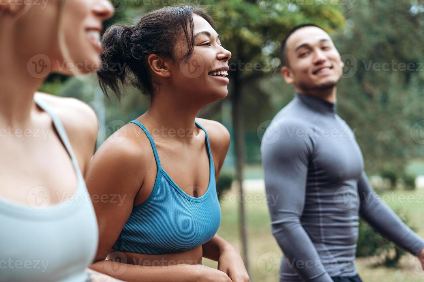 African American woman talking with diverse sportswoman and Asian man, walking, training together photo