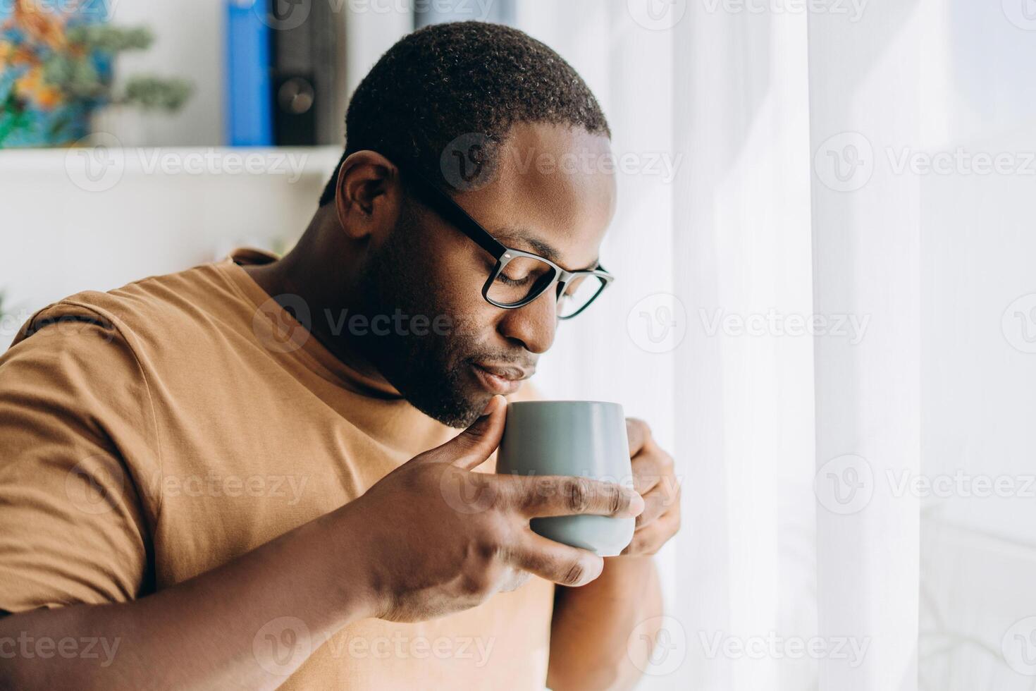 Handsome African American man in glasses drinking coffee at home photo