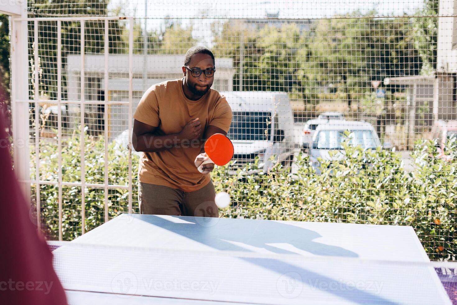 Young African American man playing table tennis outdoors photo