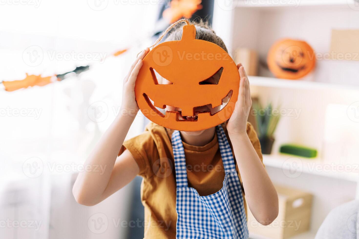 Little, fun girl holding halloween pumpkin decoration at home. decoration concept photo