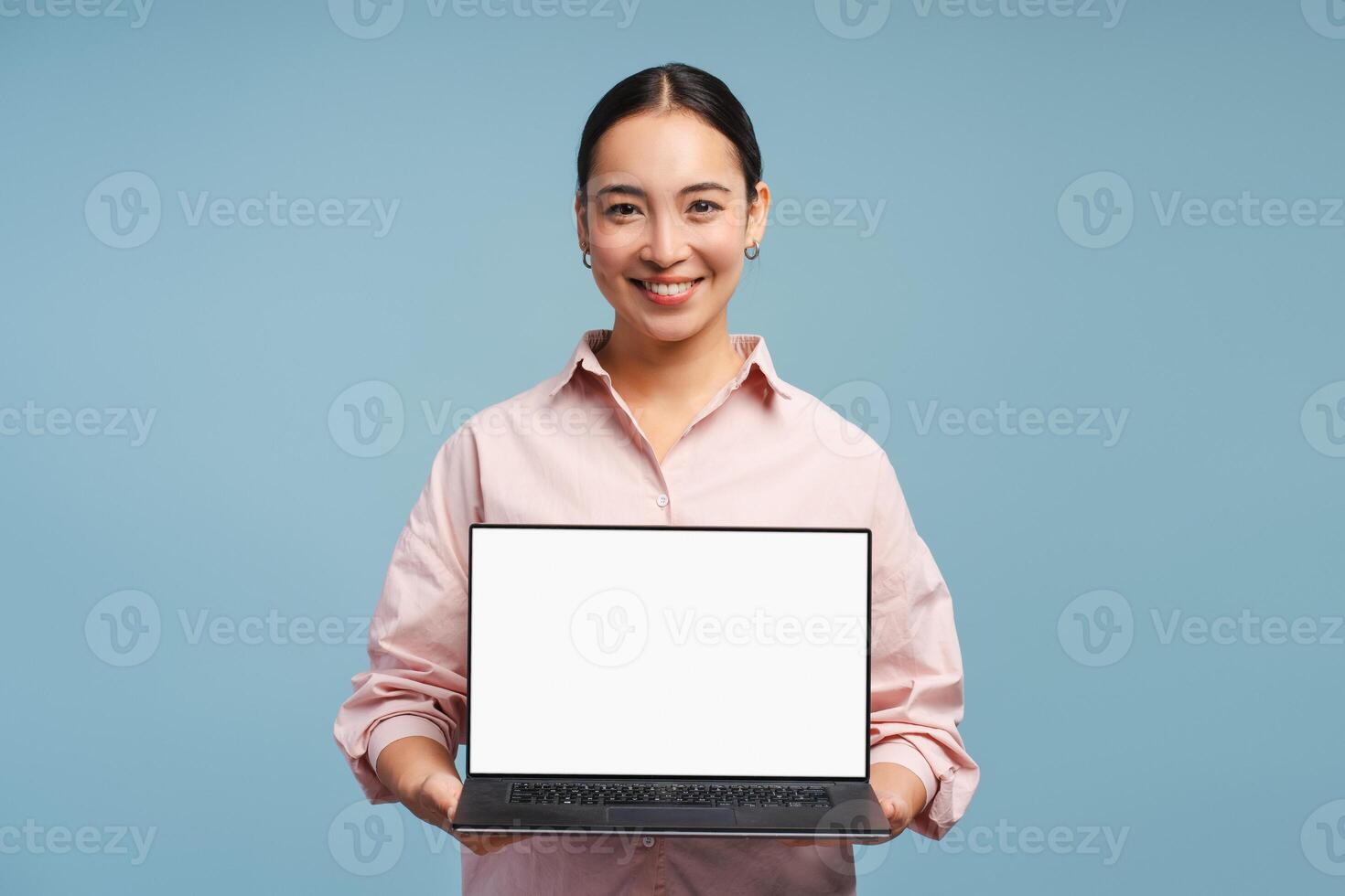 Smiling businesswoman showing laptop with blank screen on blue background photo