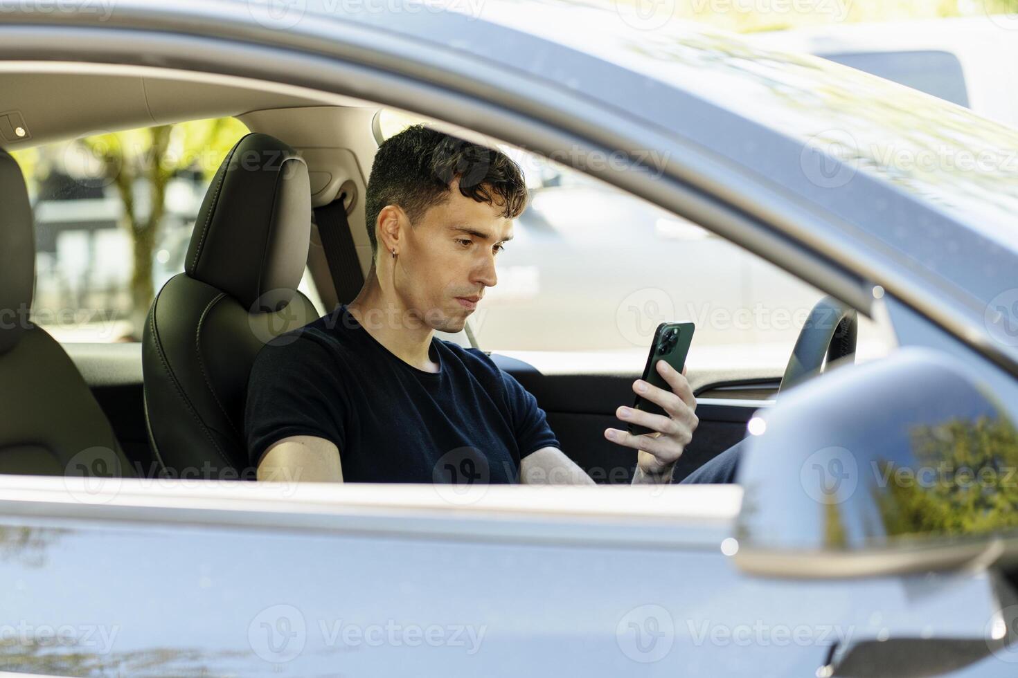 Young man using smartphone while sitting in car photo
