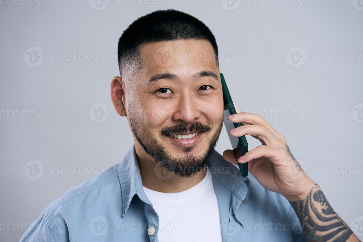 Asian man smiling while talking on the phone photo
