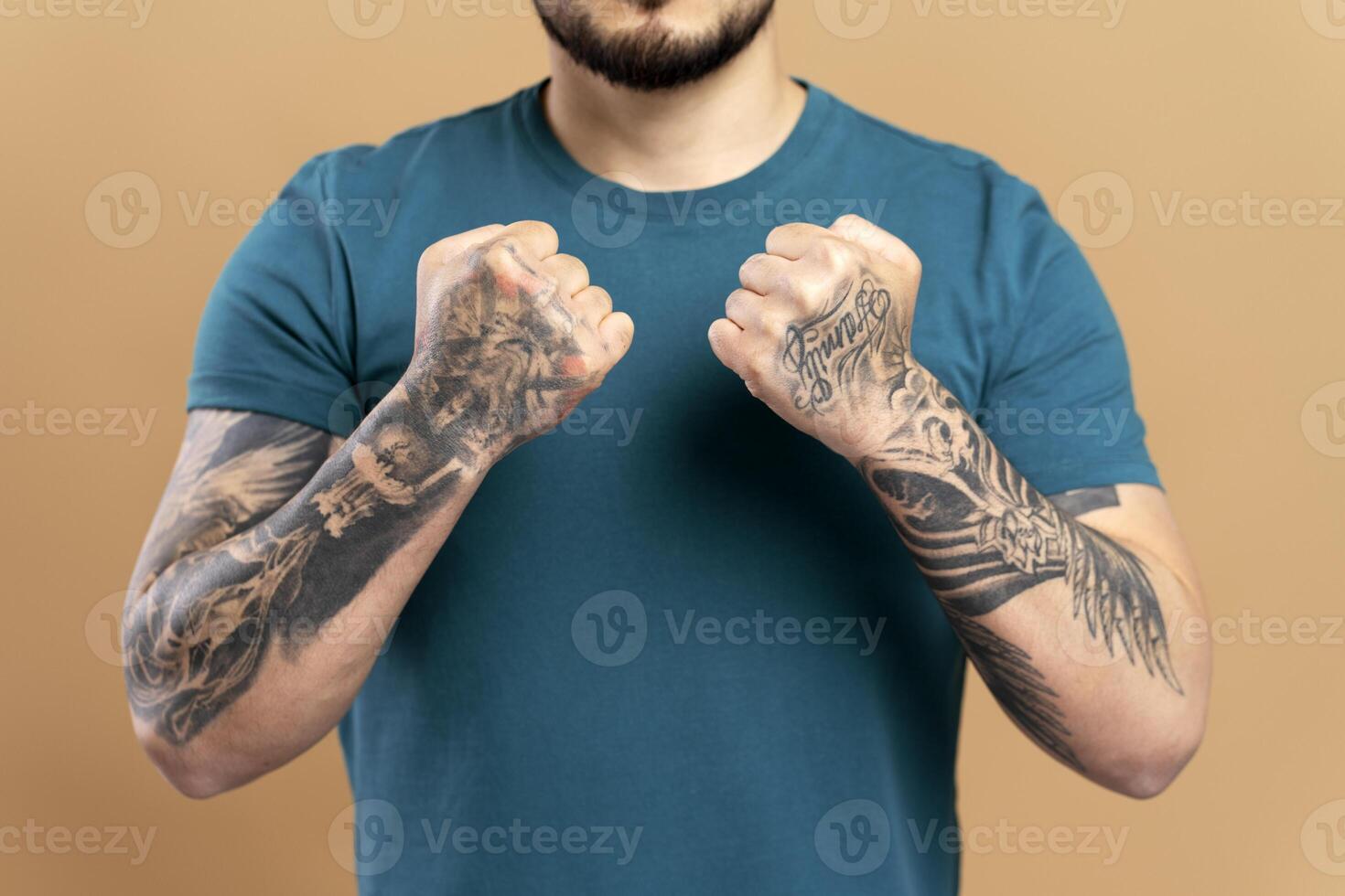 Tattooed man clenching fists on beige background photo