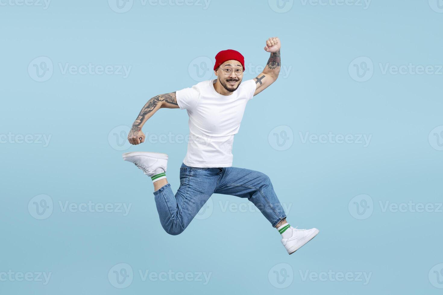 Cheerful man with tattoos is jumping and raising his fist in the air photo