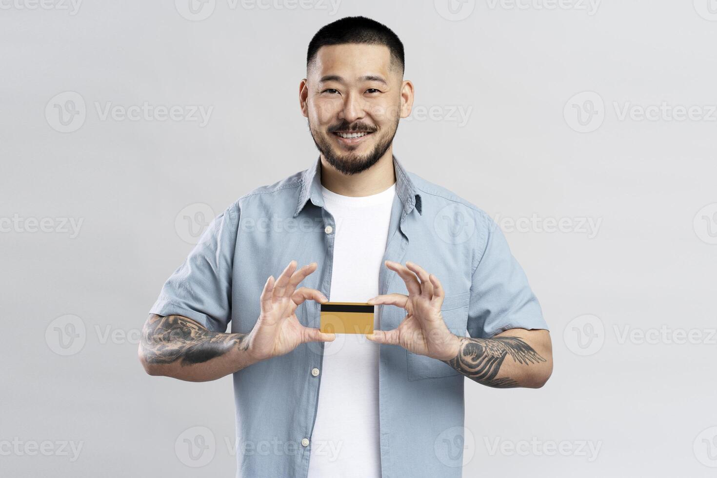 Smiling young man showing credit card on white background photo