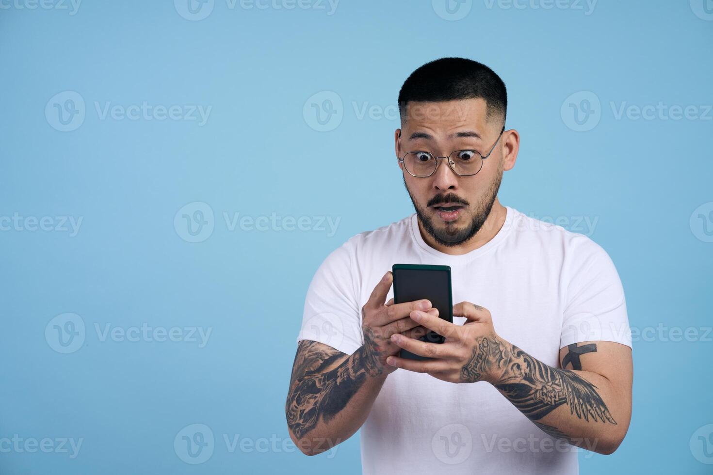 Shocked man reacting to phone content on blue background photo