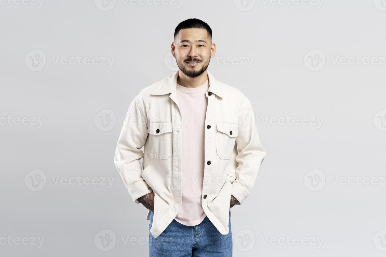 Young man smiling with hands in pockets on white background photo