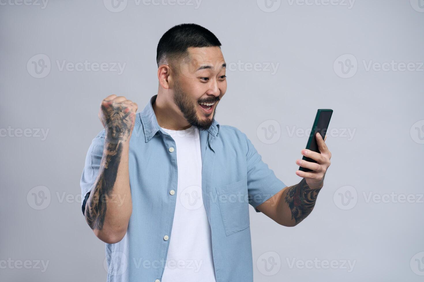 Excited bearded man celebrating success on smartphone, fist pumping in joy photo