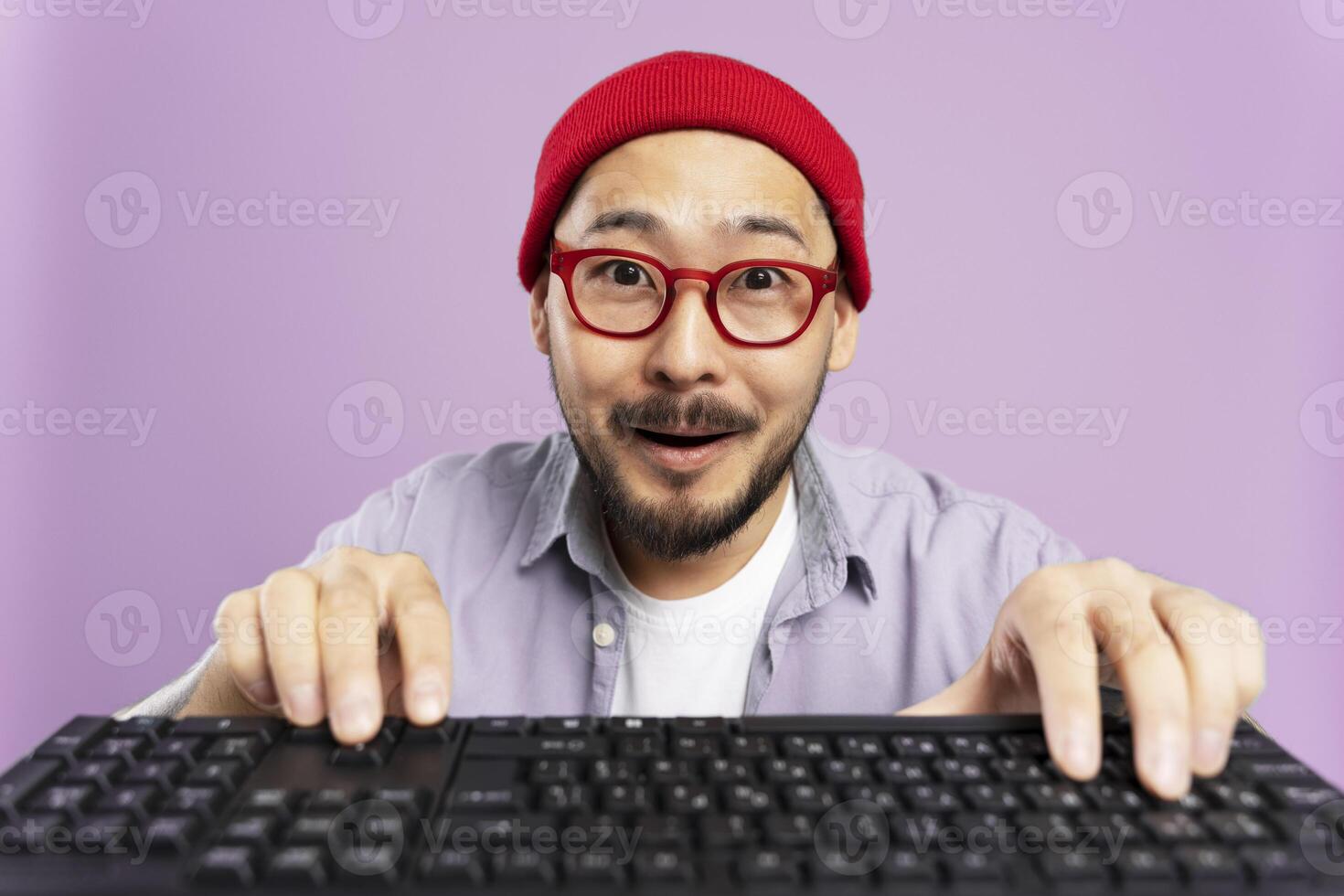 Excited asian man using a keyboard with a purple background photo
