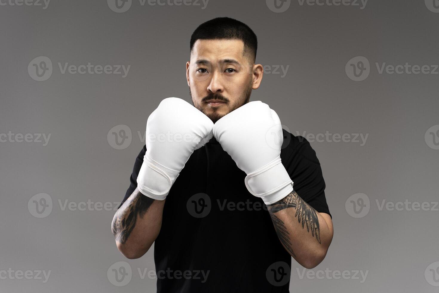 Asian boxer wearing white boxing gloves posing on grey background photo
