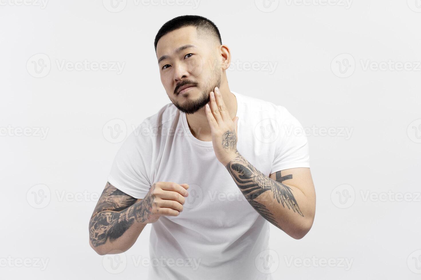 Handsome young man touching his beard looking at you photo