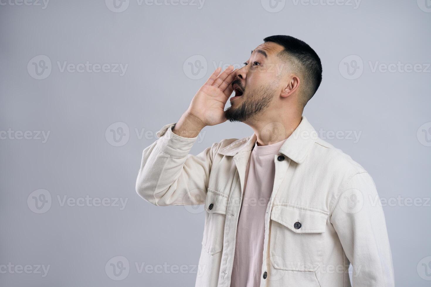 Young man shouting loudly with hand on mouth photo