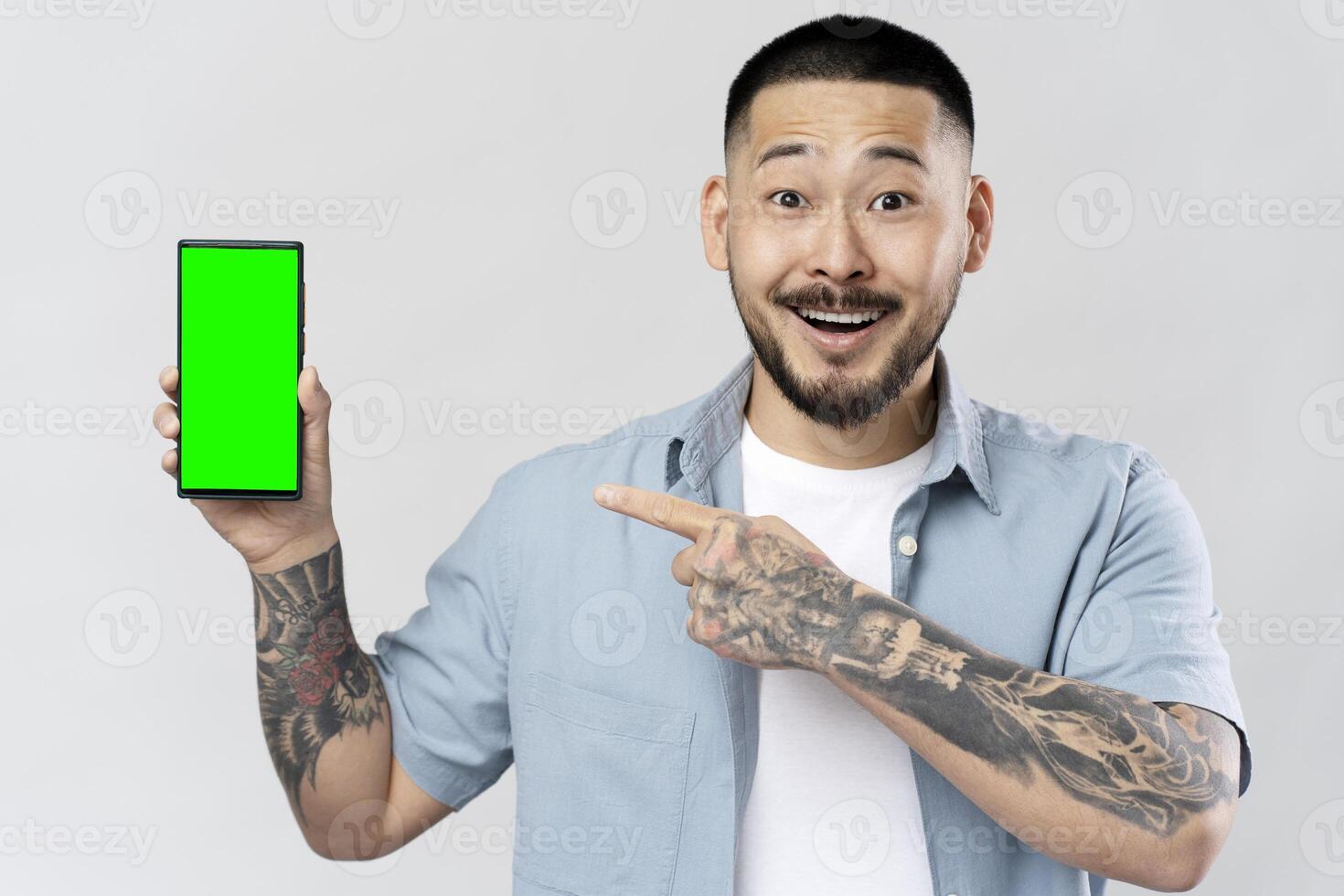 Excited man showing smartphone with green screen photo