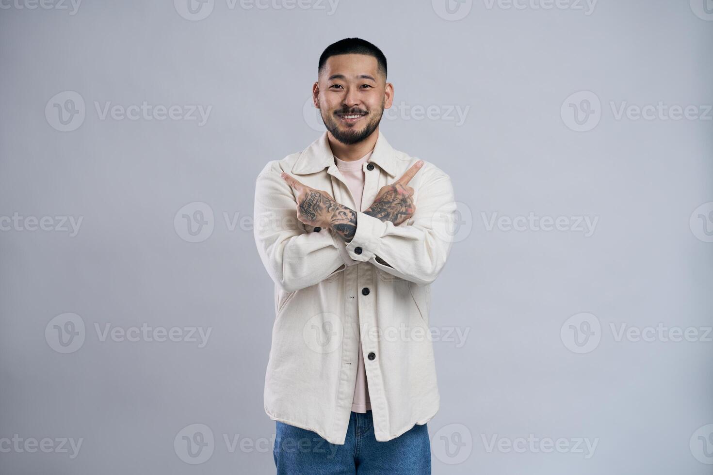 Smiling asian man pointing two index fingers sideways photo