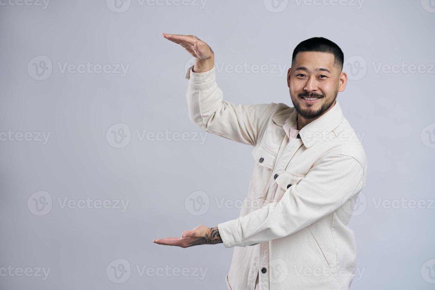 Smiling asian man showing something between hands photo